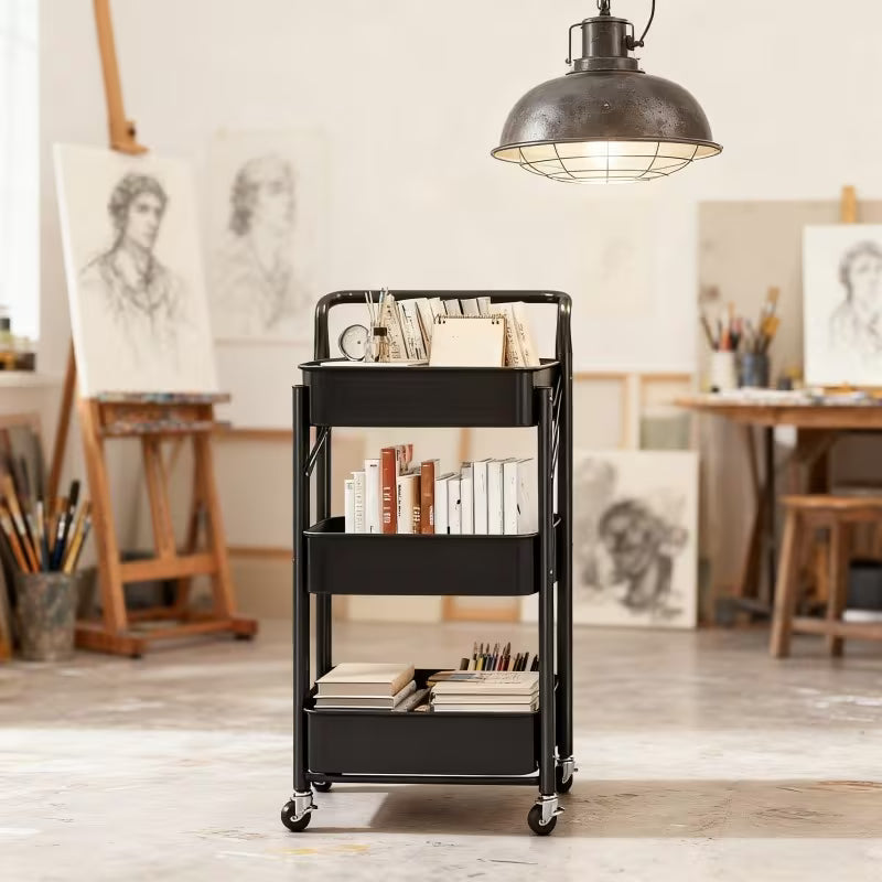 3-Tier Rolling Metal Storage Cart in an artist's studio with books and art supplies.