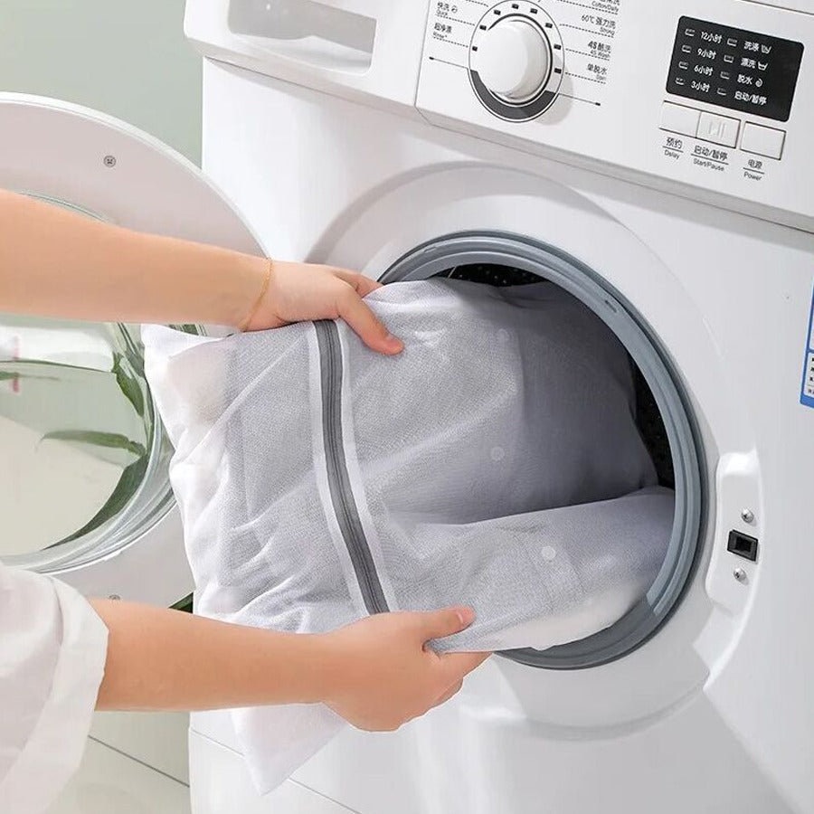 A Person is inserting cloth to a washing machine using 4 Pcs  Mesh Laundry Washing Bags Set.
