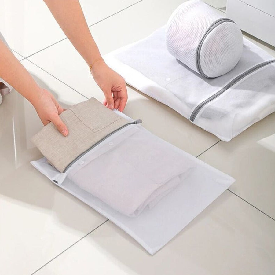 A person is keeping cloth to 4 Pcs  Mesh Laundry Washing Bags Set.