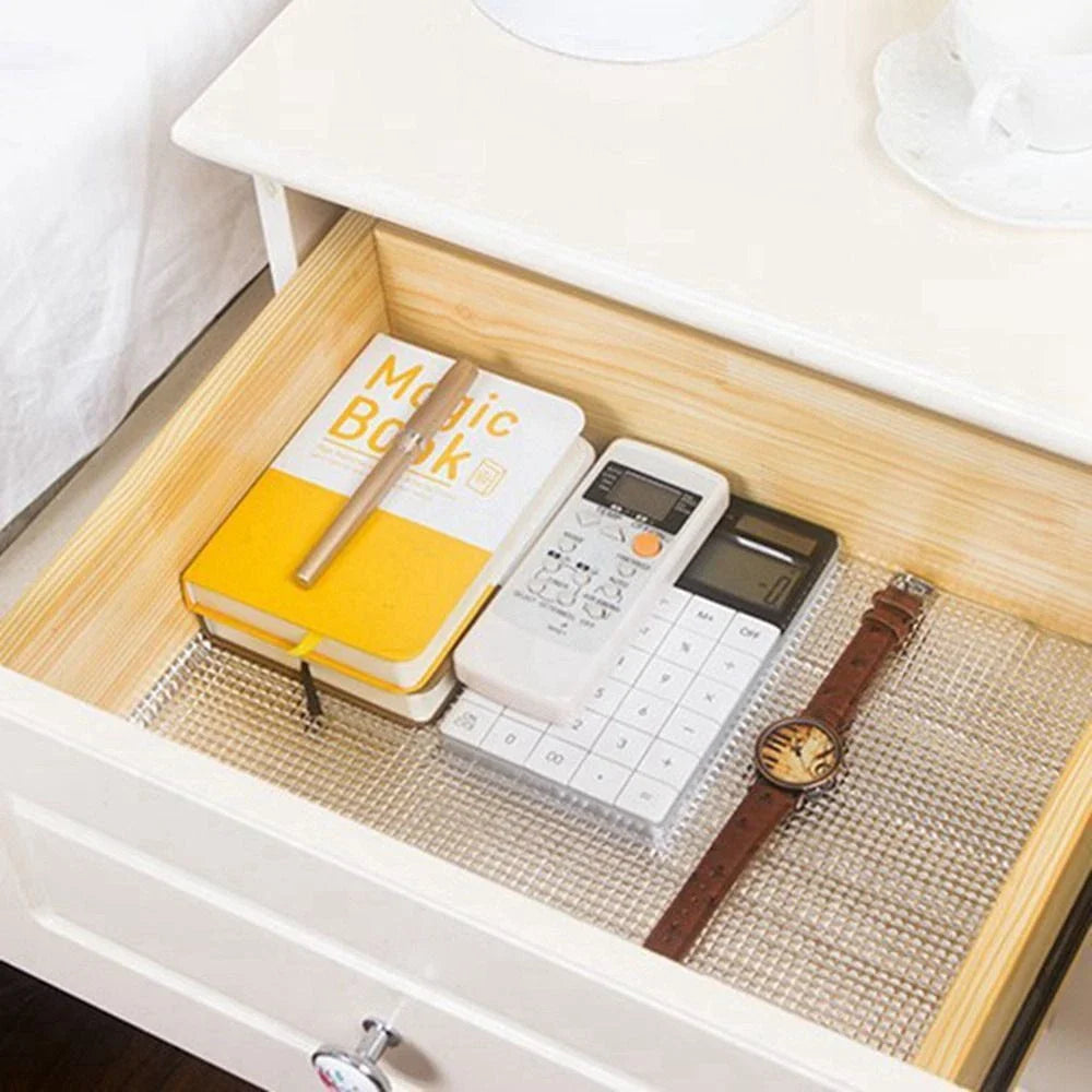 A non-slip protective sheet placed inside a drawer, neatly holding everyday items like a notebook, calculator, pen, and watch, showcasing organized and scratch-free storage.