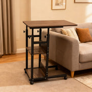 An adjustable overbed laptop table placed in a cozy living room, featuring a sofa with decorative cushions.
