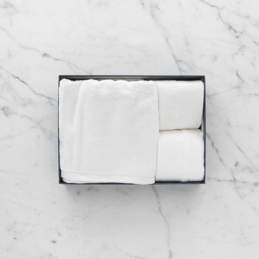 White folded Cotton Bath & Face Towel Set in a black box on a marble surface