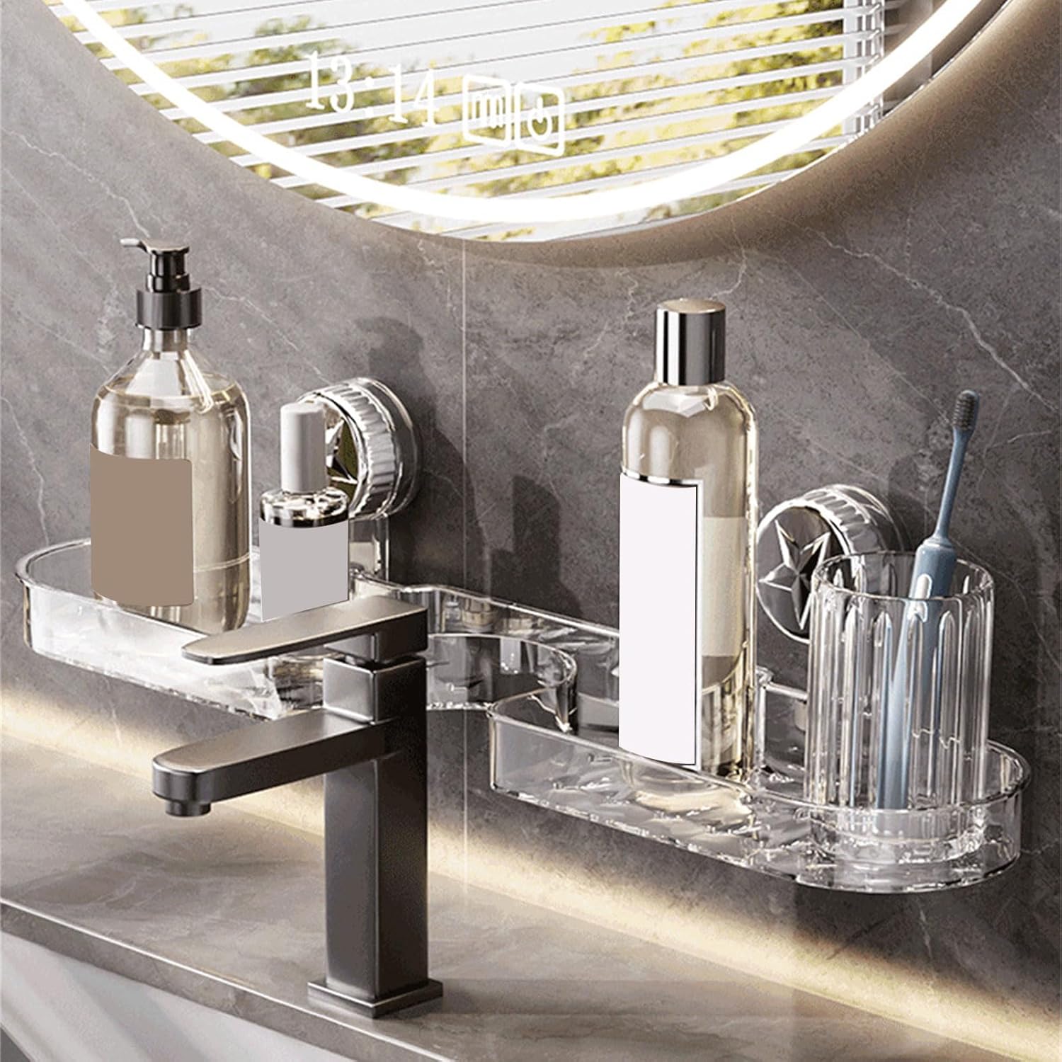Clear suction bathroom shelf mounted on a tiled bathroom wall above a sink, holding soap dispensers, skincare bottles, and a toothbrush holder beside a modern black faucet.