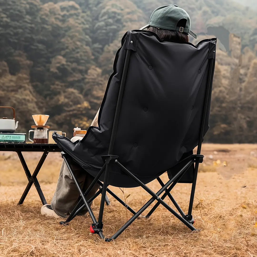 A Person is using Green Lion Travix Camping Chair in a Camping area.