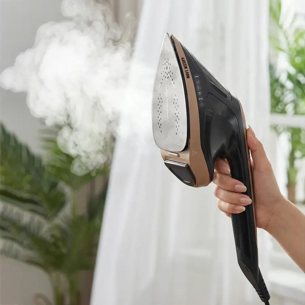 Person using a Green Lion 2-in-1 Steam Iron Garment Steamer on a white fabric with a blurred indoor background