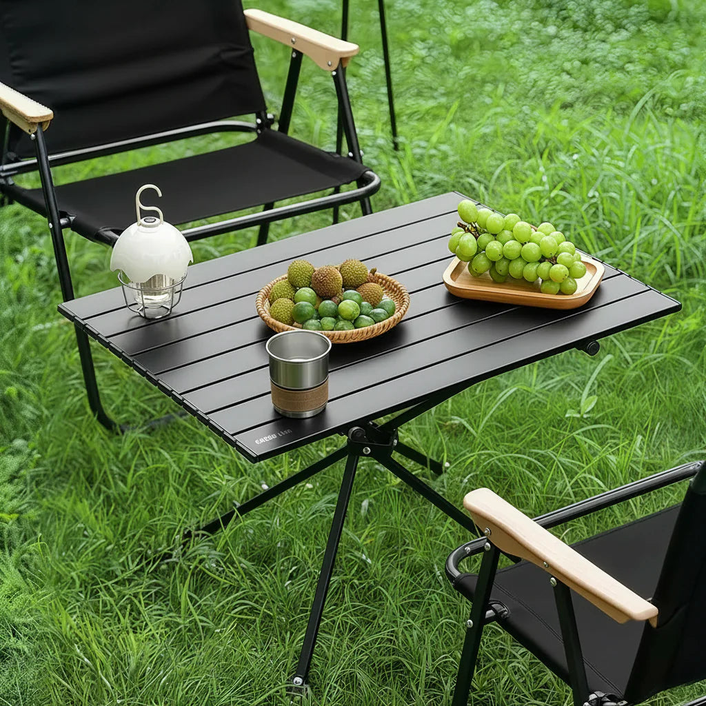 Green Lion Camp T2 Foldable Camping Table with chairs, drinks, and snacks on a grassy outdoor setting