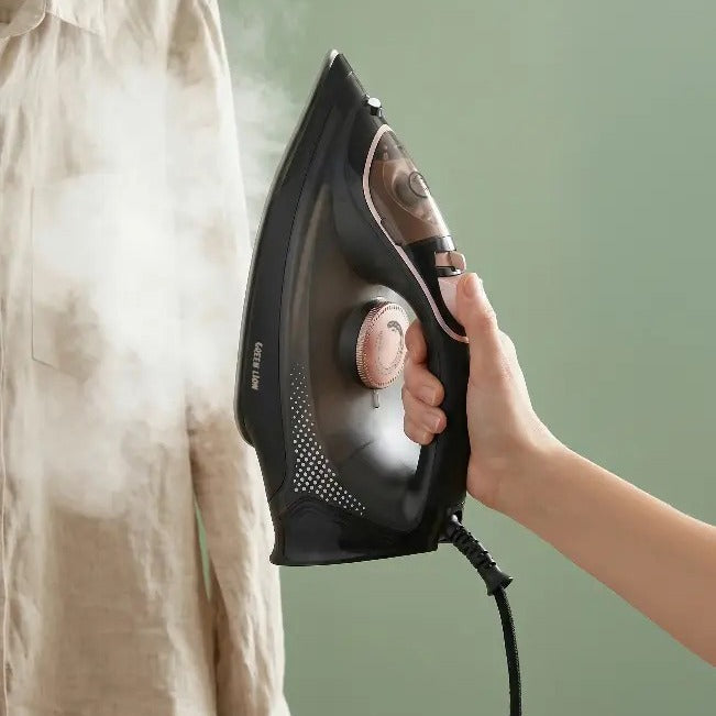 Person ironing a shirt with a Green Lion Steam Iron on a green background