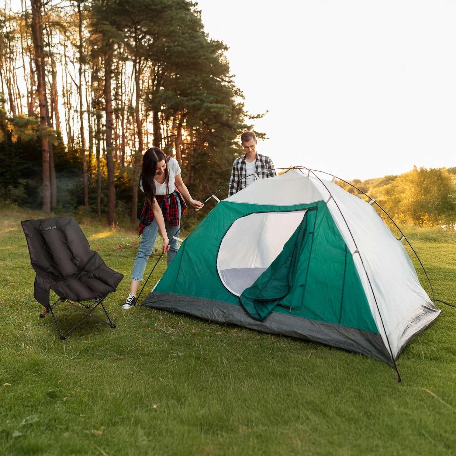 Two people setting up a green and gray tent in a grassy field with Green Lion Travix Camping Chair.