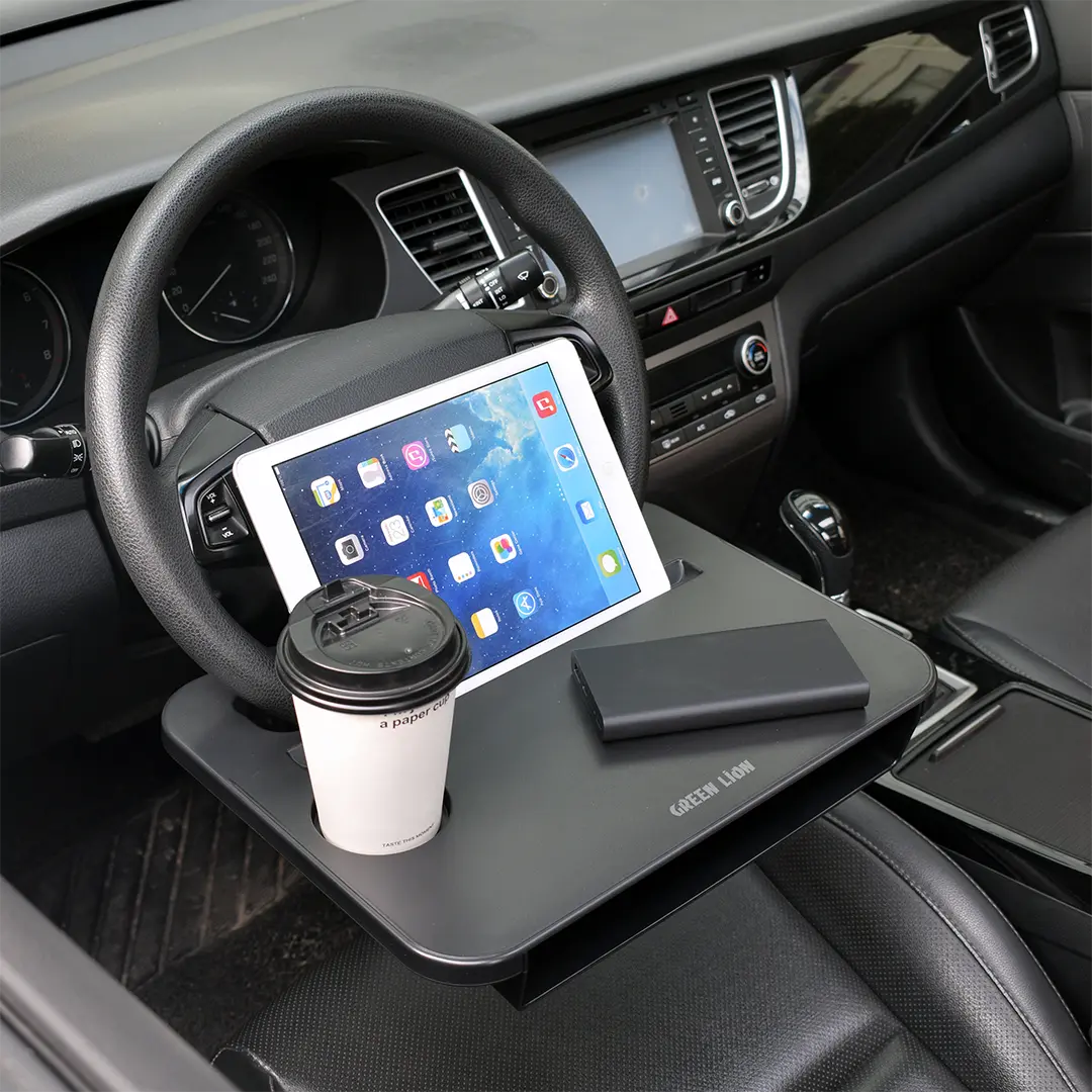 A Green Lion steering wheel tray holding a tablet, coffee cup, and power bank inside a car, showcasing a convenient in-car workspace