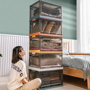 A woman sits beside a stackable plastic storage boxes 