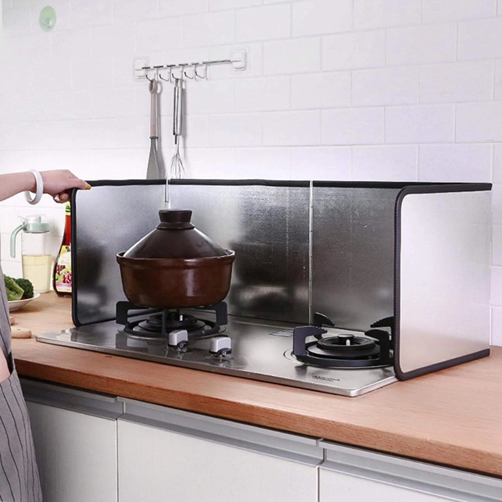 A woman placing a pot on a gas stove,utilizing an oil-blocking board