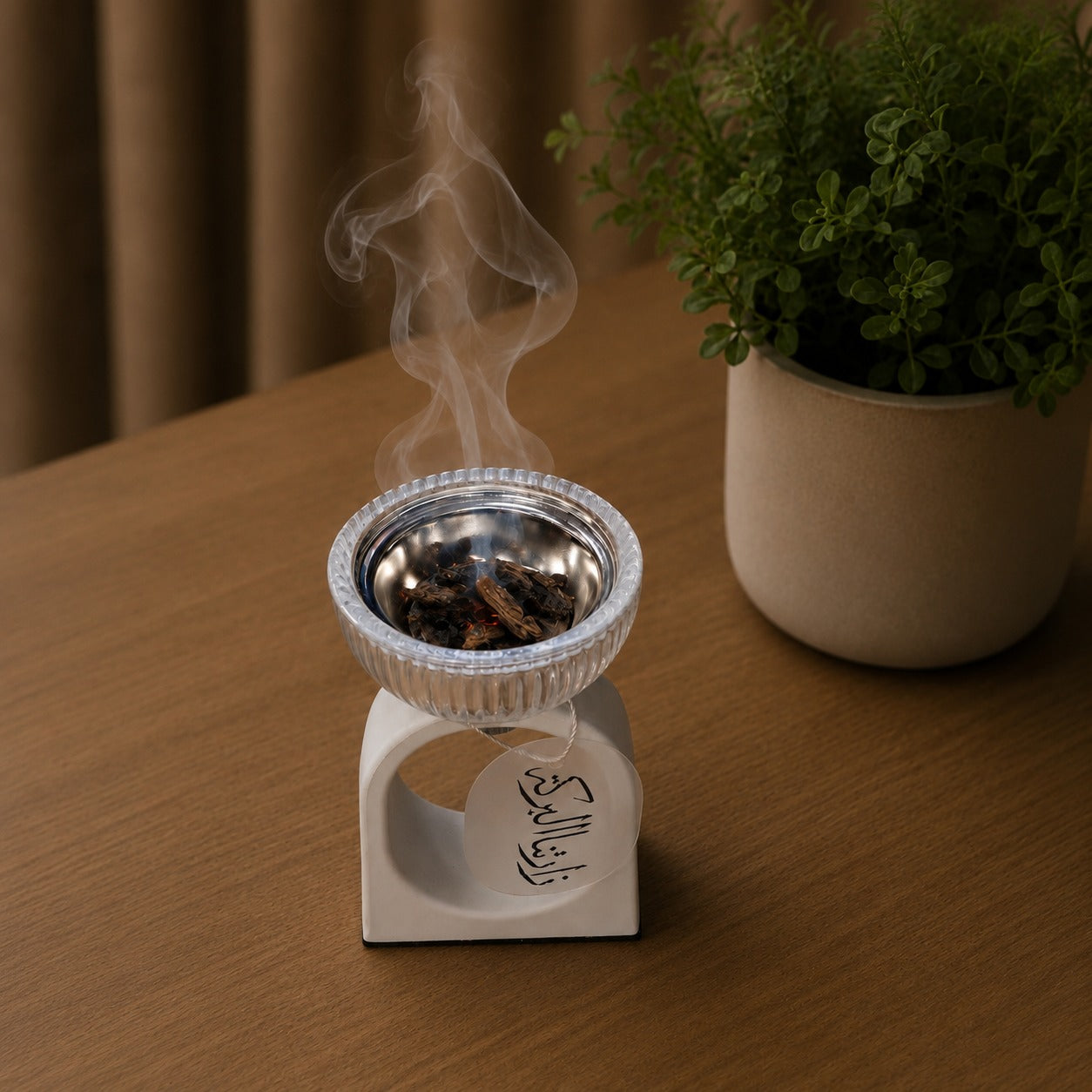 Incense burner with smoke on a wooden surface next to a potted plant