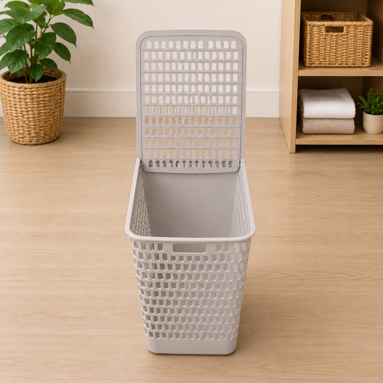 Gray woven laundry basket on a wooden floor with a plant and shelves in the background.