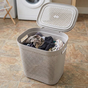 Laundry basket with clothes on a tiled floor next to a washing machine
