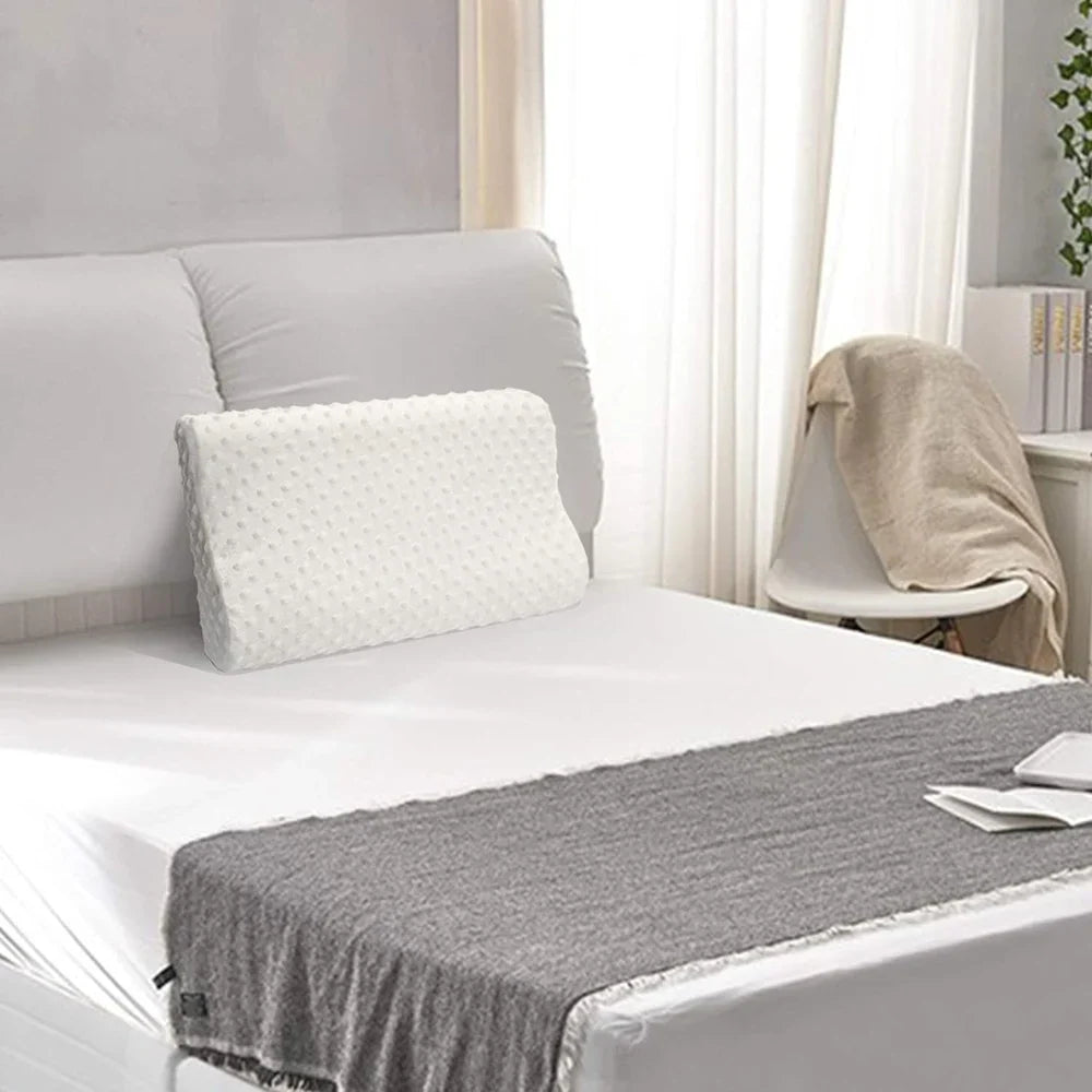 A white memory foam pillow placed on a neatly made bed in a calm, modern bedroom setting