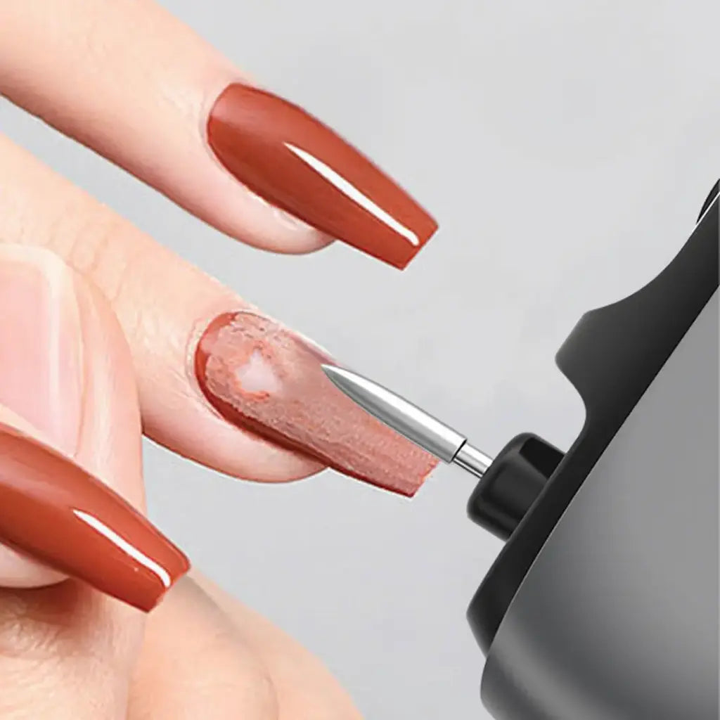 A person applies brown nail polish to their fingernail using the Porodo Multi-Function Electric Nail Clipper against a gray background.