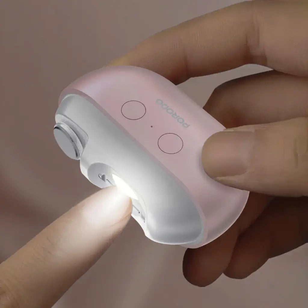 Hand holding a Porodo Multi-Function Electric Nail Clipper with a light on a neutral background