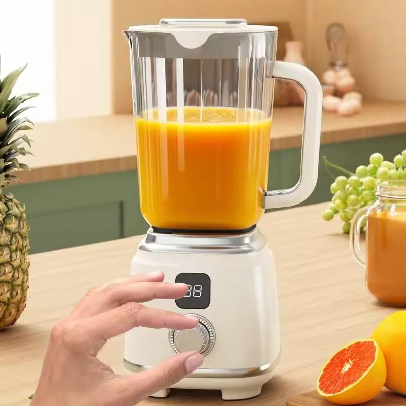 A person using a white portable citrus juicer blender to prepare fresh orange juice on a kitchen counter, surrounded by assorted fruits
