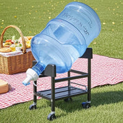 Outdoor picnic setup with a large water jug on a metal stand with wheels.