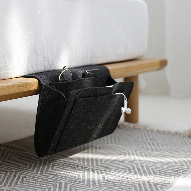 Felt Bedside Storage Bag placed next to the bed with some items