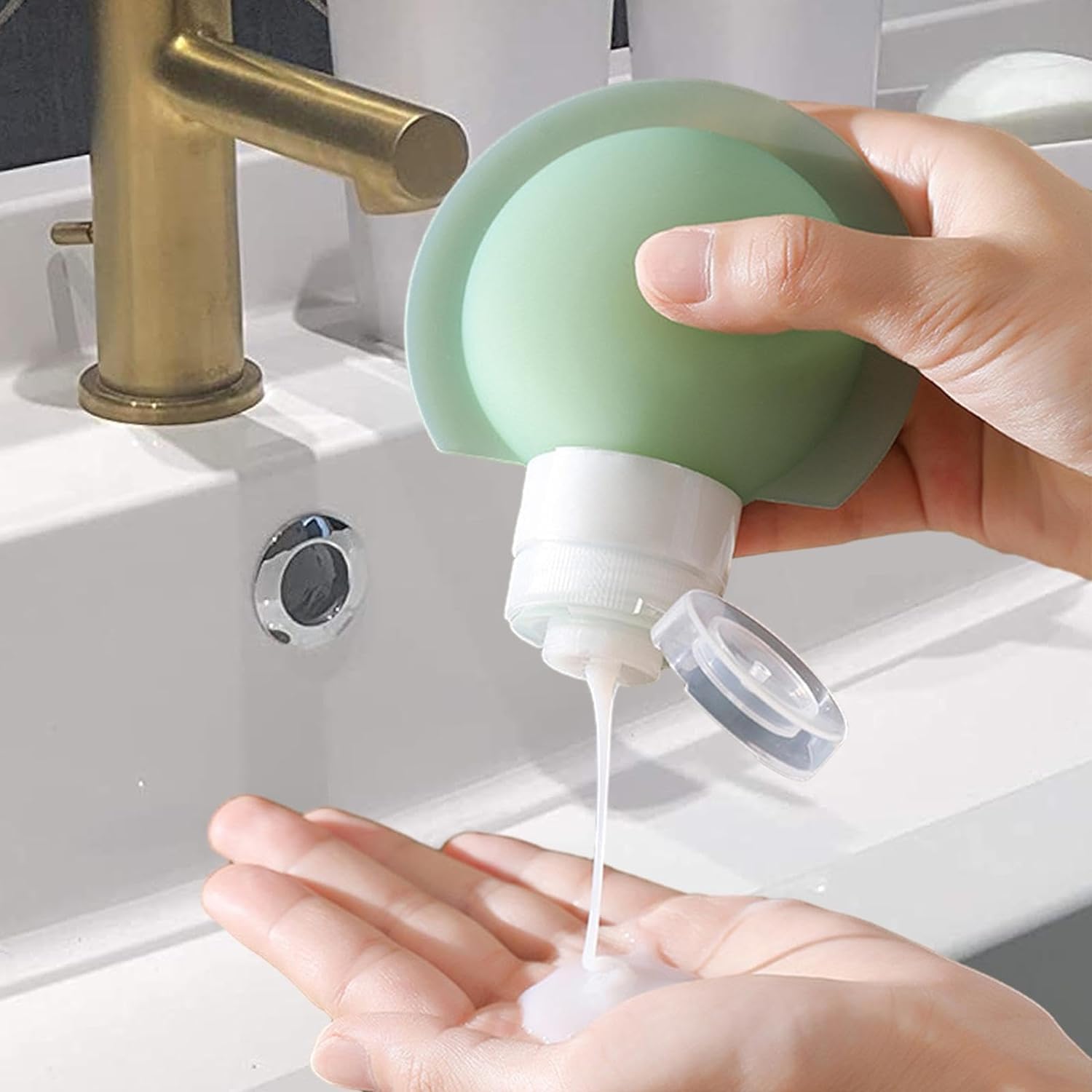 Hand using a Silicone Travel Bottle Set to dispense soap into hands with a sink in the background