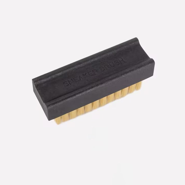 Black scrubber brush of Sneaker Cleaning Kit with wooden handle on a white background