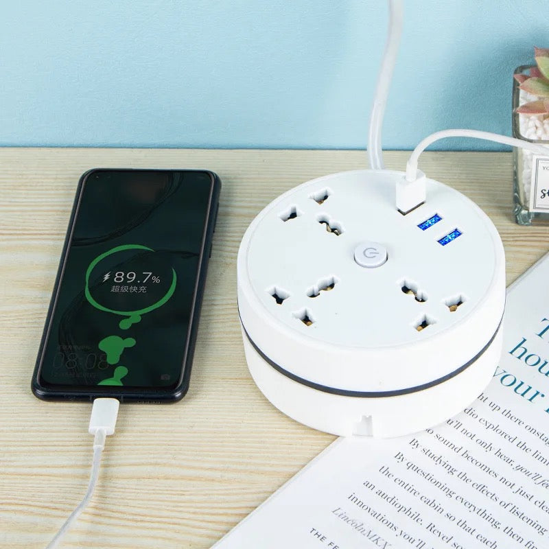 Round Universal Converter Power Strip Adapter placed on desk next to a mobile which is plugged into the power strip