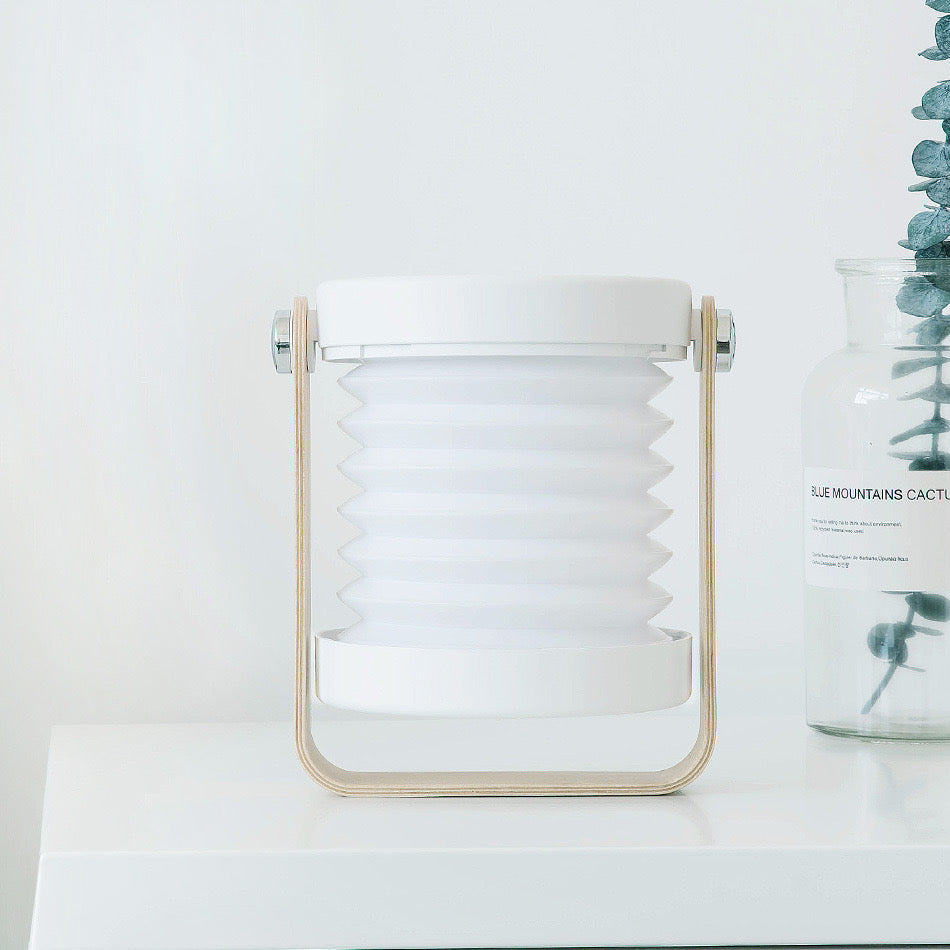 Retractable Table Lamp with USB Rechargeable, placed on a table next to a vase