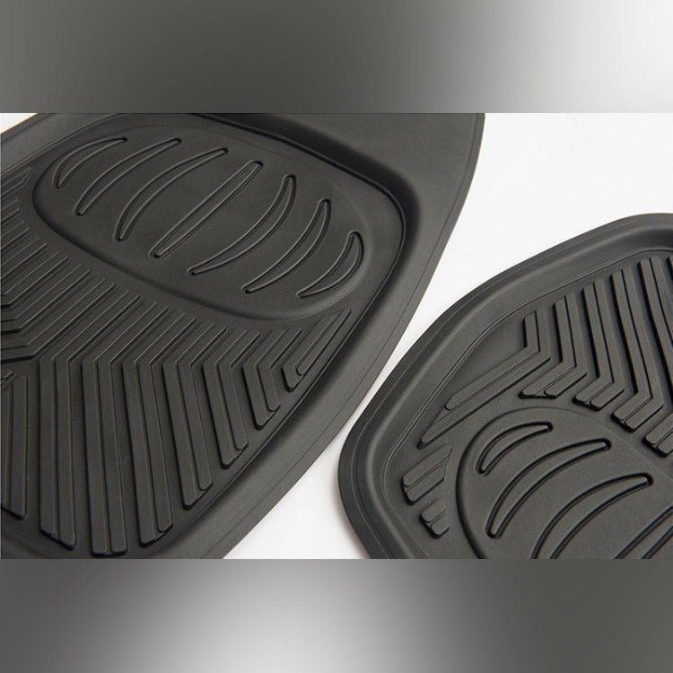 Two black rubber car mats with textured surface on a white background