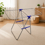 Foldable clothes drying rack in a room with a rug, plant, and basket.
