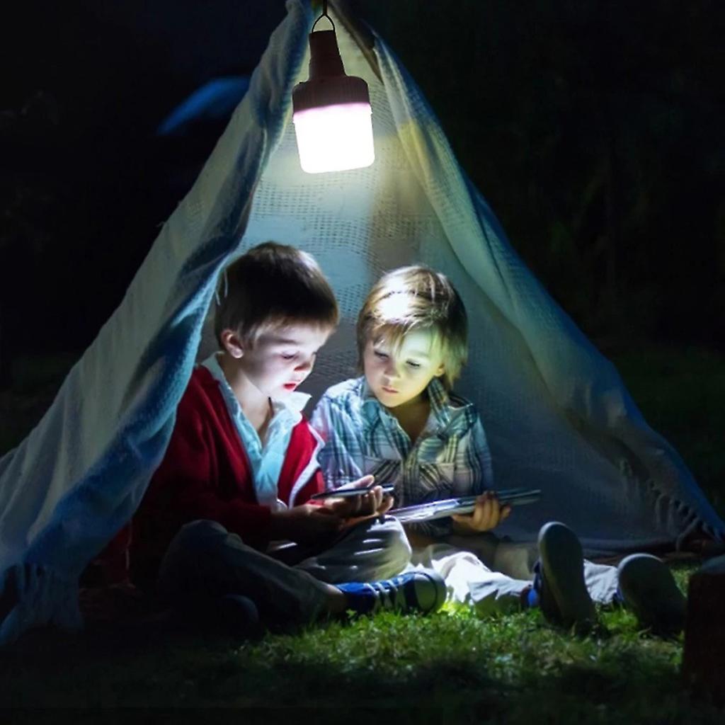Children sitting inside a small tent at night illuminated by a solar rechargeable LED bulb, creating a cozy and bright lighting scene.