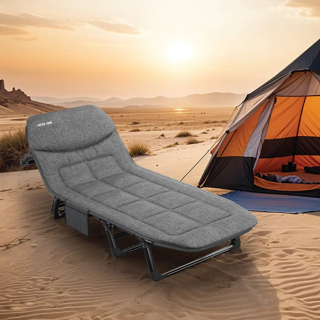 Green Lion Foldable Camping Bed in front of an orange tent in a desert landscape with sunset.