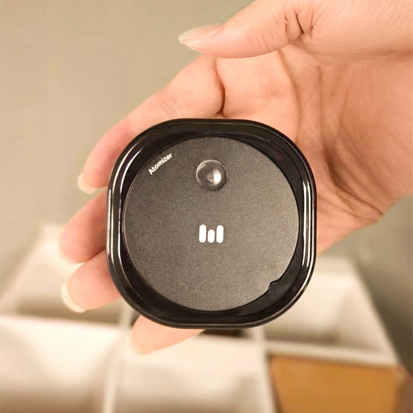 Hand holding a Macnoa MacX mistFlow Electric Coffee Atomizer with a brand logo on a neutral background